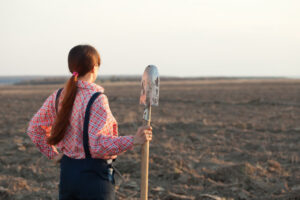 Dig into your story female farmer with spade in plowed field